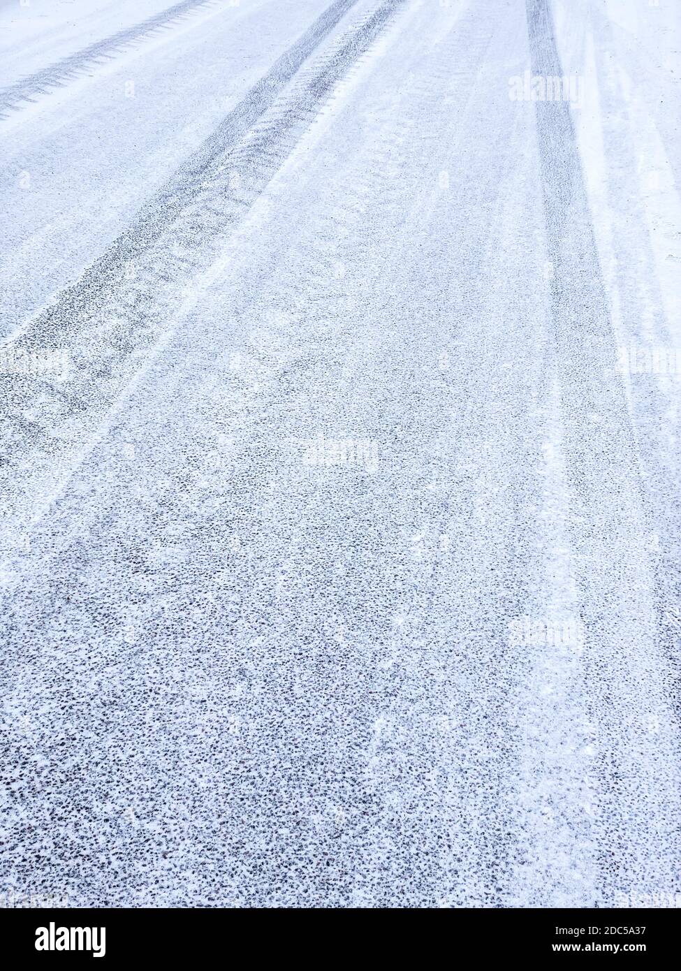 route asphaltée recouverte de neige et de traces de pneus. chaussée après la neige Banque D'Images