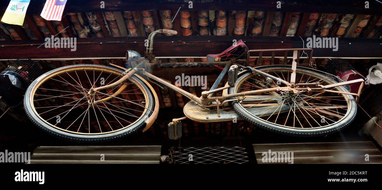 Un ancien vélo d'époque suspendu au plafond d'un bâtiment rustique en bois. Banque D'Images