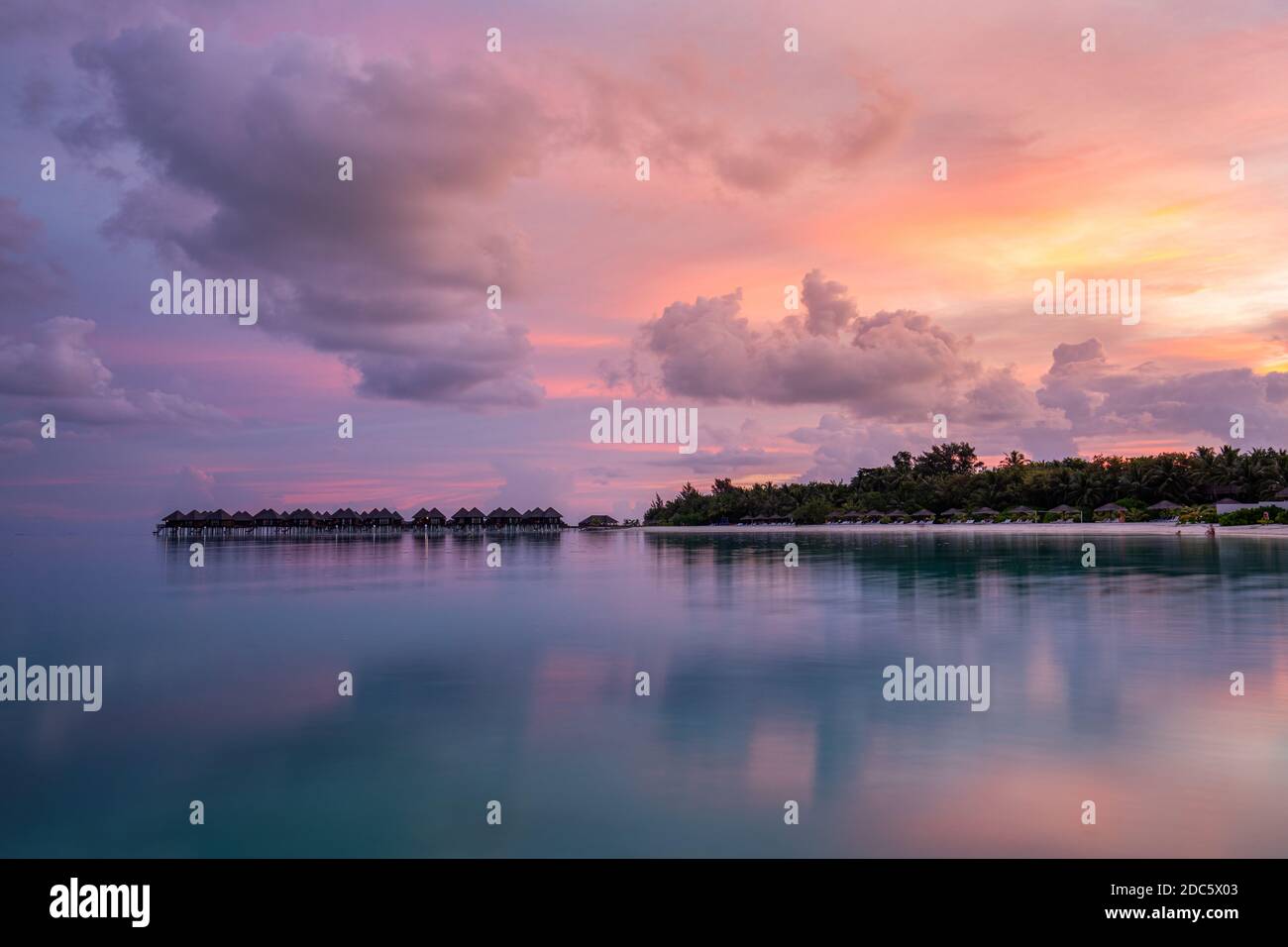 Bungalows au-dessus de l'eau avec reflet de lagon incroyable. Ciel coloré nuages sur l'île tropicale. Paradis d'été, paysage de luxe. Destination pittoresque Banque D'Images