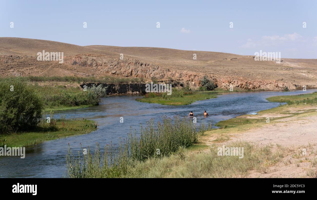 Kurty, Kazakhstan - 22 juillet 2019: Deux personnes nageant dans le fleuve Kurty près de Kurty entouré acheter steppe un jour d'été. Banque D'Images