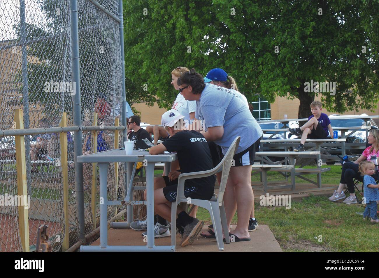Le jeu de softball pour filles a marqué les gardiens derrière la clôture de chaînette lors d'une journée d'été au Kansas. Banque D'Images