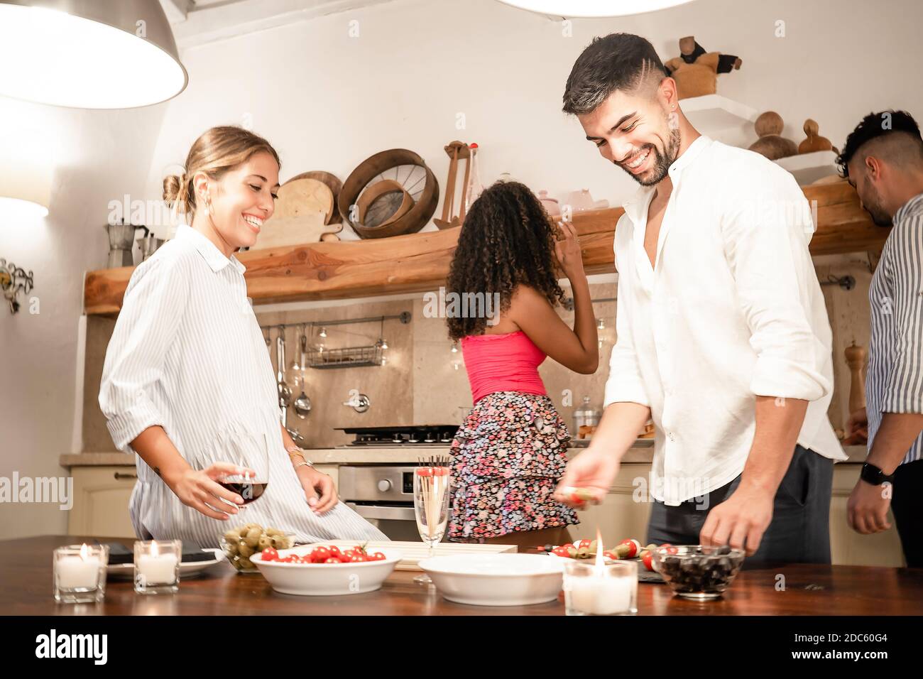 De beaux amis de la génération du millénaire se sont joint à la maison pour préparer des collations Apéritif - deux couples hétérosexuels s'amusant ensemble dans le cuisine Banque D'Images
