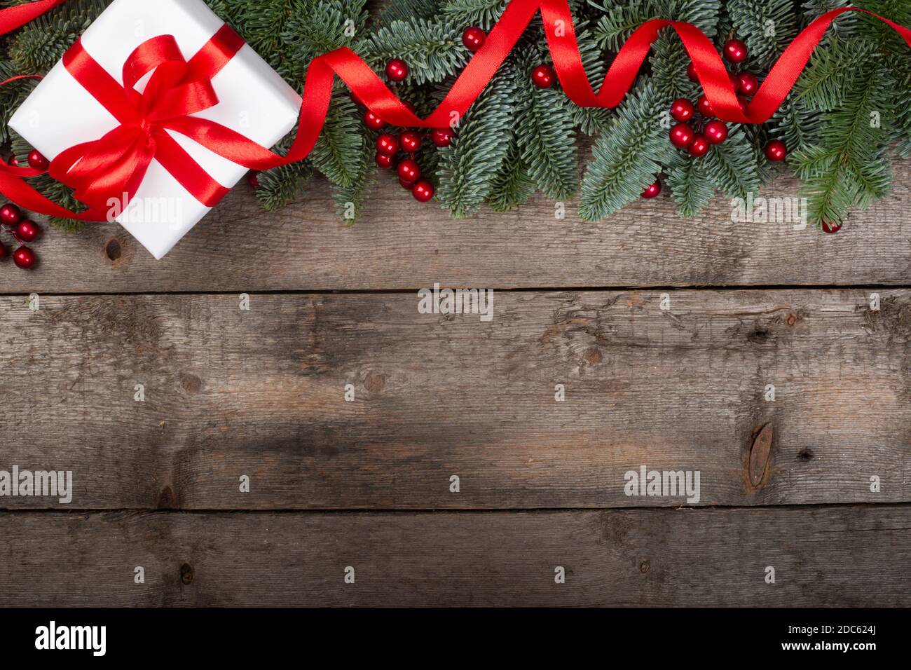 Brindilles de sapin de Noël et cadeau avec ruban rouge sur fond en bois avec espace de copie pour le texte Banque D'Images