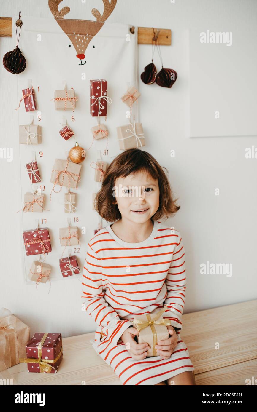 Adorable fille ouvrant Noël calendrier de l'Avent cadeaux. Cadeaux emballés pour les enfants. Tradition saisonnière. Noël écologique Banque D'Images