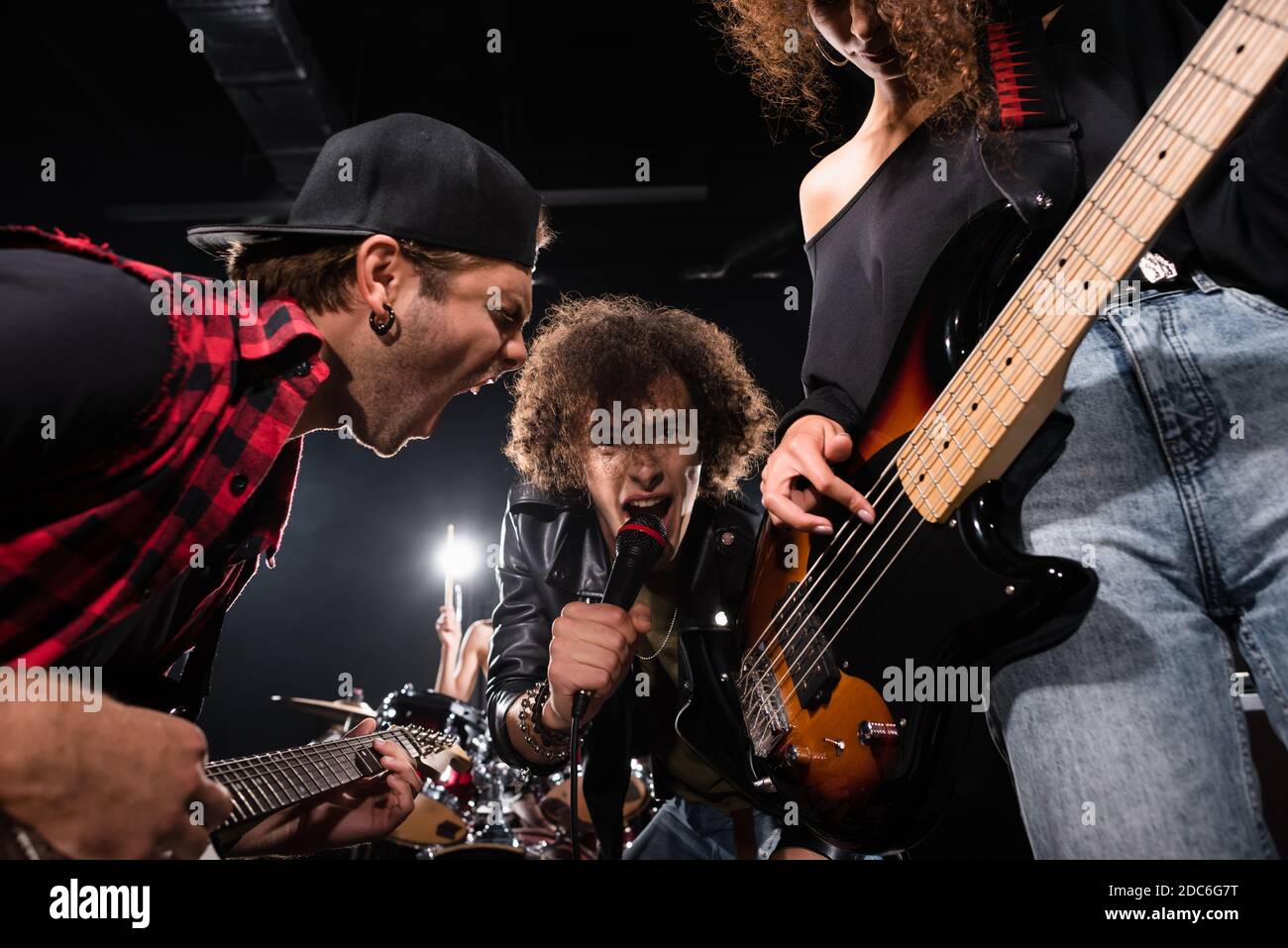 KIEV, UKRAINE - 25 AOÛT 2020 : vue en contre-angle d'un chanteur maussal regardant un appareil photo tout en criant avec un guitariste rétroéclairé sur fond flou Banque D'Images