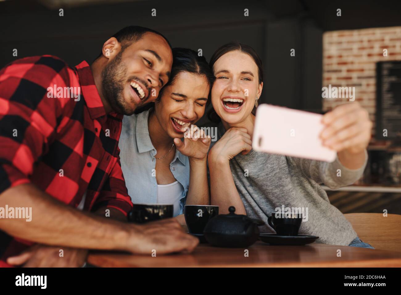 Femme prenant selfie avec des amis dans un café. Amis dans le café-restaurant s'amuser et prendre des selfies. Banque D'Images
