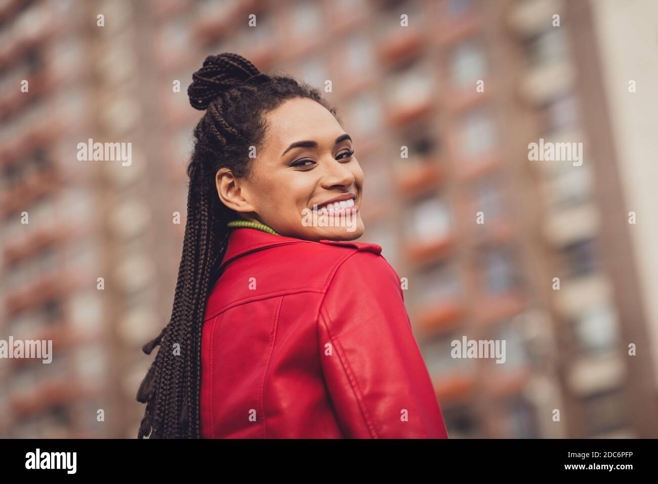 Photo de jeune fille africaine joyeux cheveux bruns heureux sourire positif marcher ville porter veste en cuir Banque D'Images