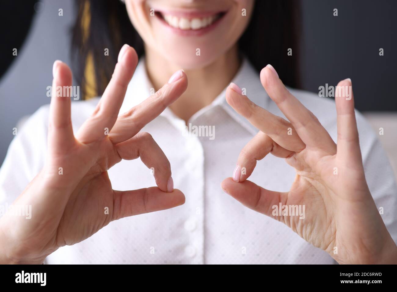 Femme d'affaires tient son doigt en geste d'ok. Banque D'Images