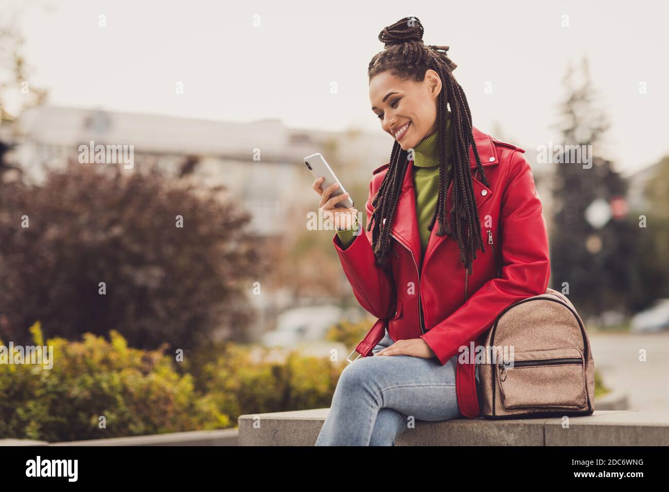 Photo de jeune fille de cheveux bruns afro joyeux sourire asseyez-vous utilisez un smartphone comme post repost chat blogger porter des jeans centre ville Banque D'Images