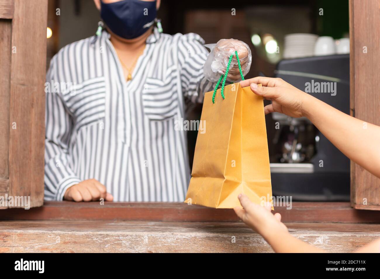 Social distance concept serveuse donnant le sac à emporter au client au café. Banque D'Images