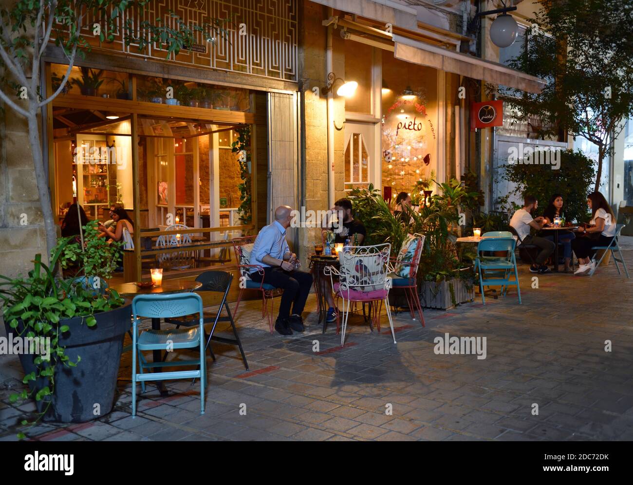 Tables, chaises et clients sur le trottoir devant le restaurant de Pieto dans la vieille ville de Nicosie et de voir à l'intérieur par la porte, Chypre Banque D'Images