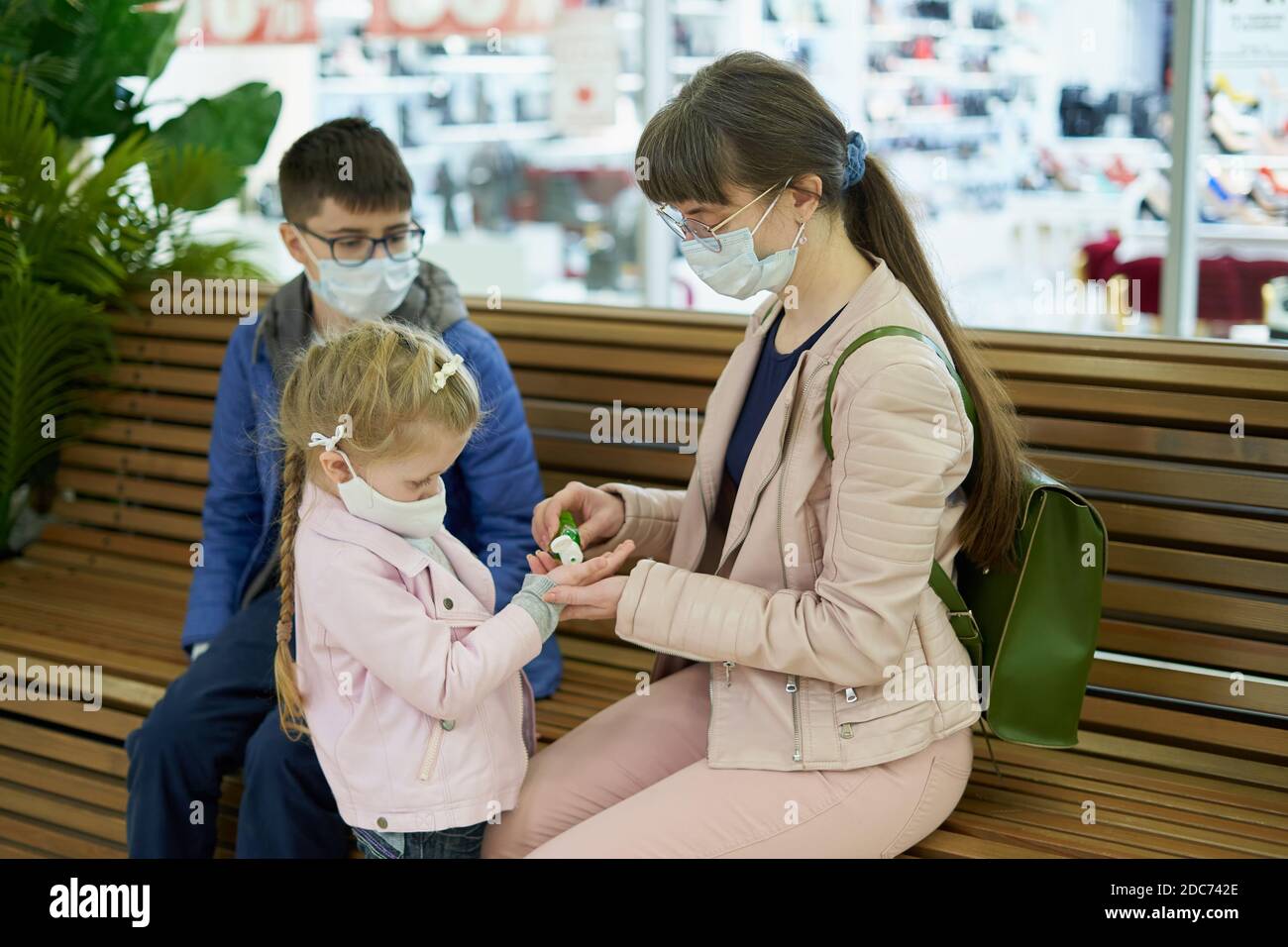 Maman traite les mains de l'enfant avec du gel désinfectant dans le centre commercial Banque D'Images