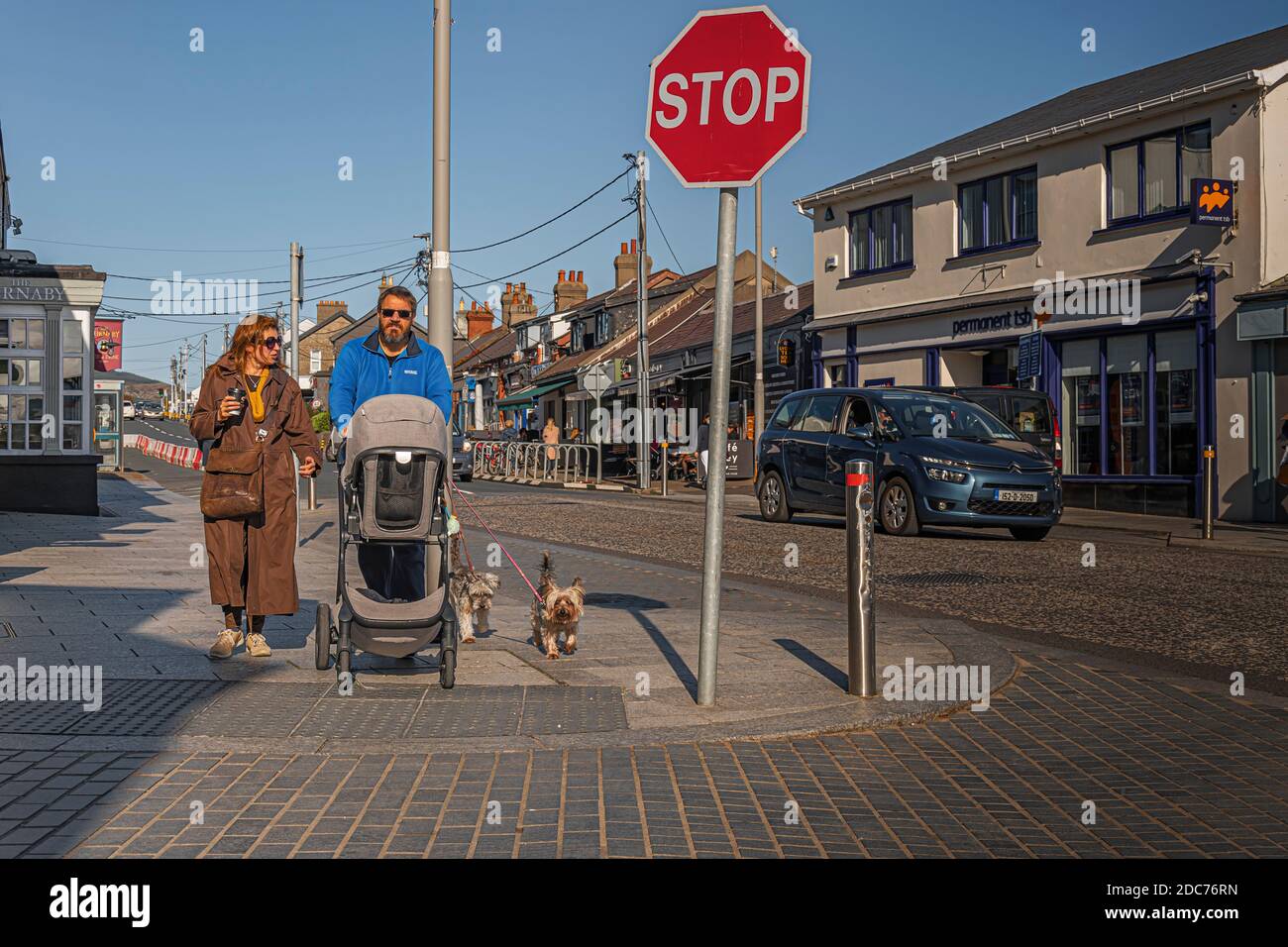 La vie quotidienne. Couple avec enfant en pram et chiens prêts à traverser la route. Banque D'Images