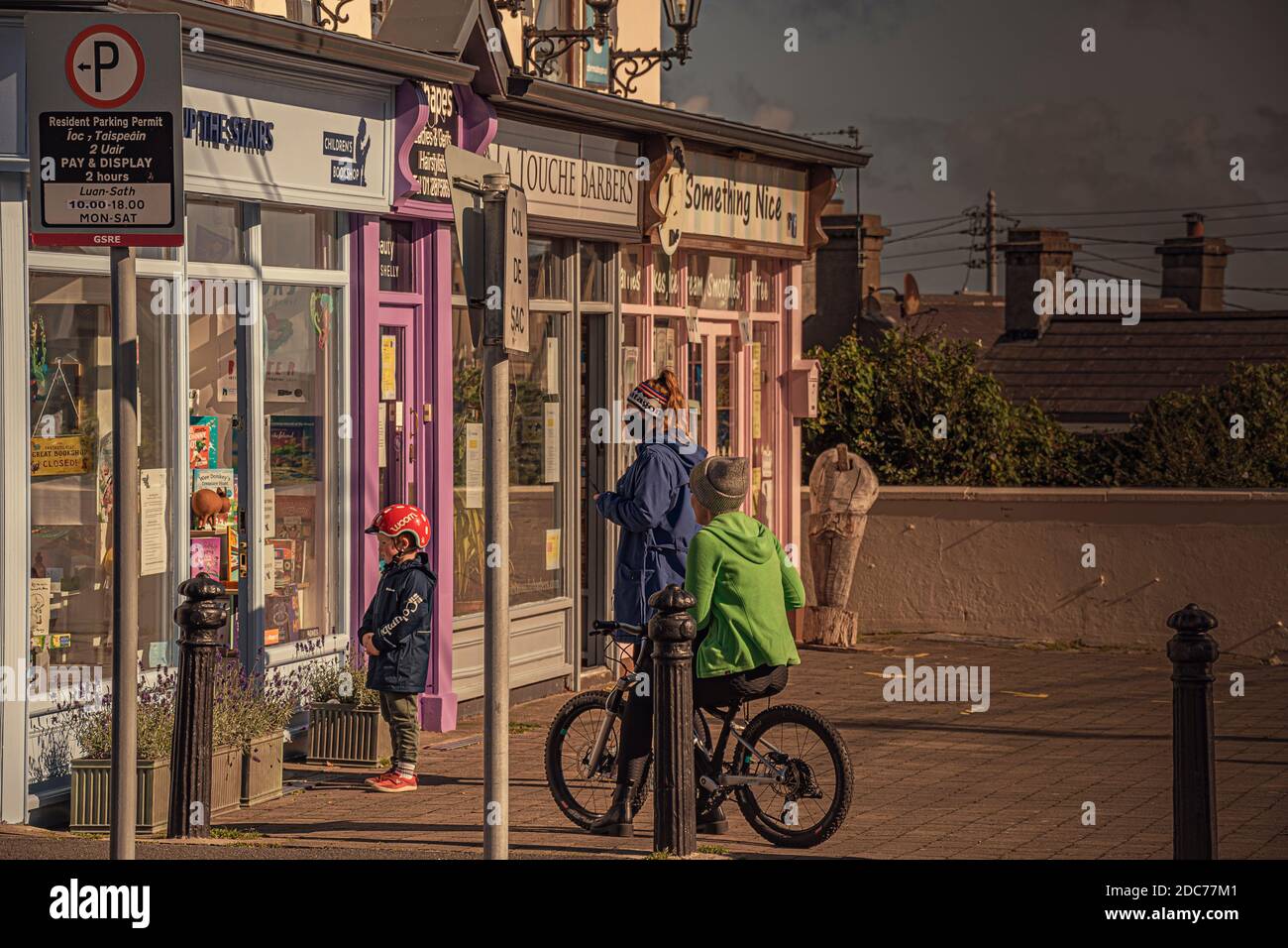 Nouvelle normale. Enfant dans un casque de vélo regardant la porte du magasin fermé avec la bannière Covid avec sa mère. Banque D'Images