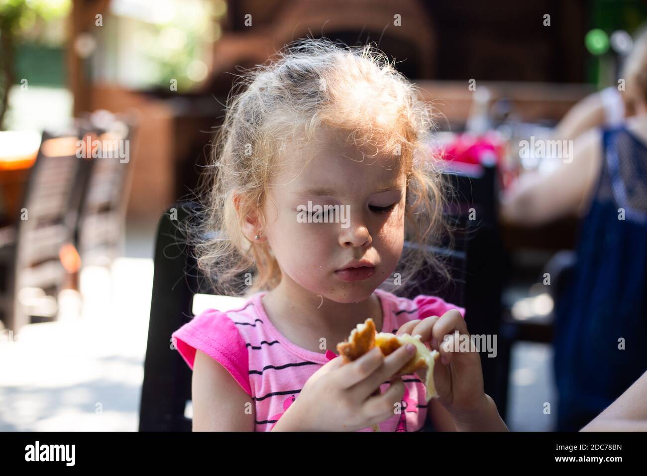 Petite fille blonde qui mange au restaurant Banque D'Images