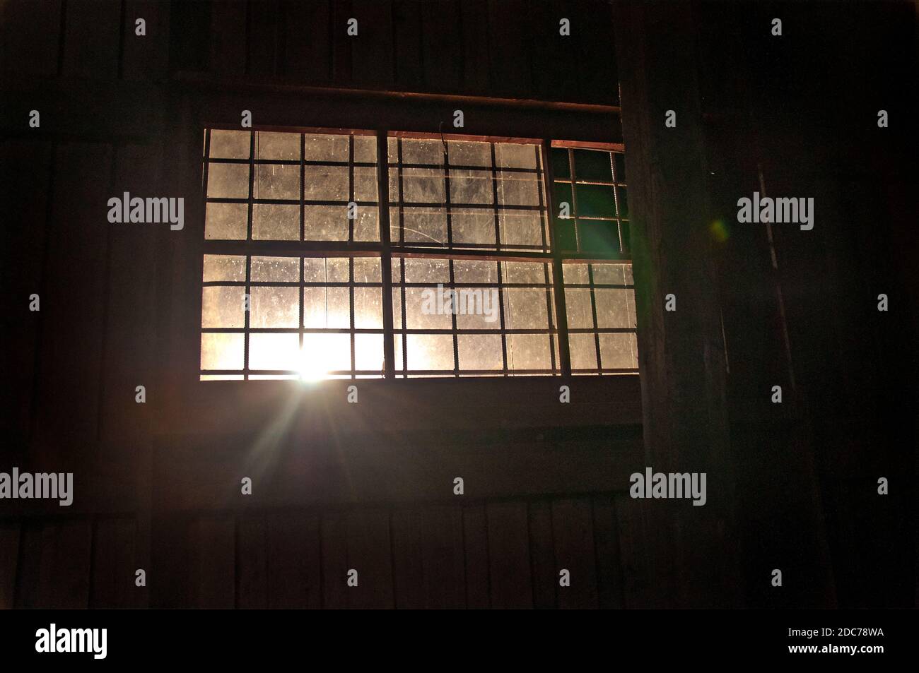 Vue sur l'ancienne fenêtre dans la caserne militaire. Un rayon de soleil à travers la fenêtre. Une image de décrépitude ou de catastrophe naturelle. Banque D'Images
