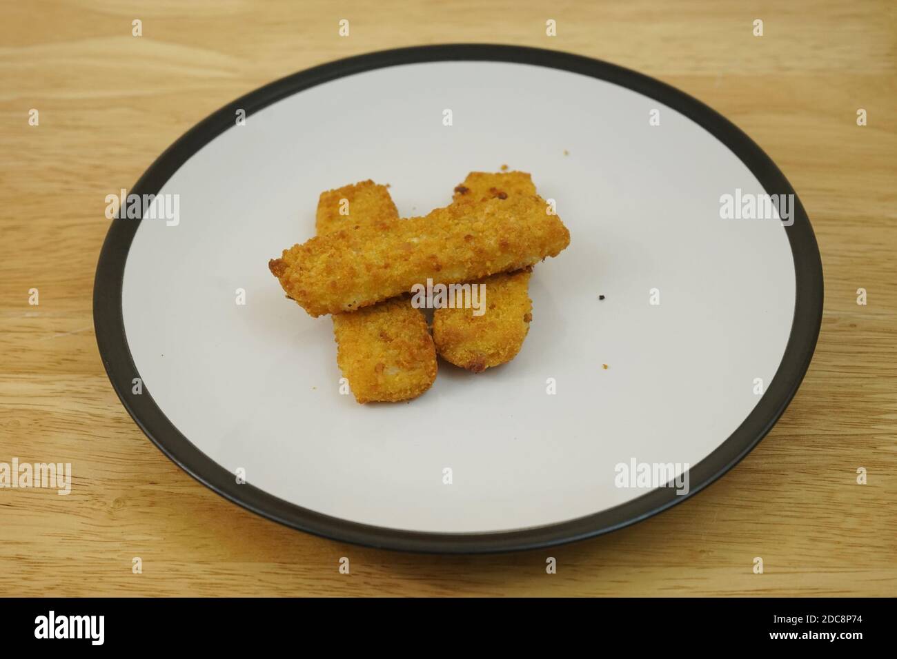 Trois doigts de poisson de morue sur une assiette pleine Banque D'Images