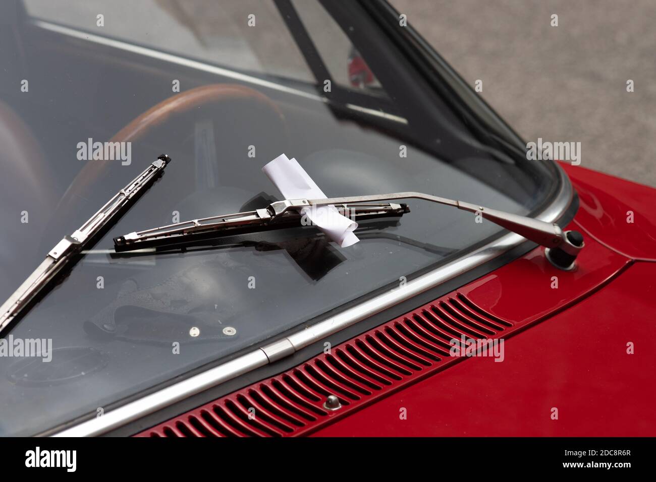 Gros plan d'un billet de violation de stationnement derrière un essuie-glace sur une voiture classique Banque D'Images Gros plan d'un billet de violation de stationnement derrière un essuie-glace sur une voiture classique Banque D'Images