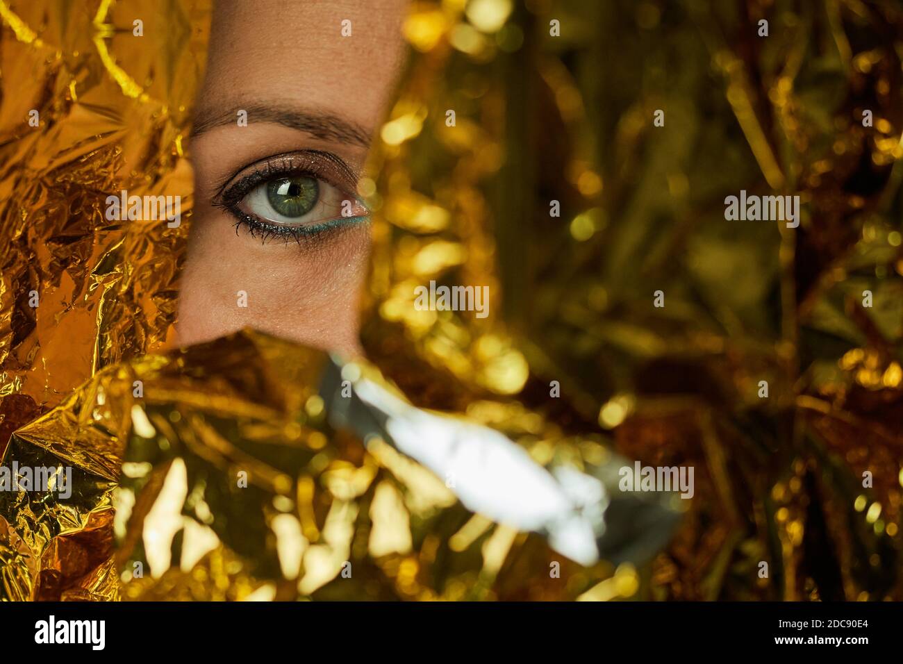 Regard vert d'une femme portant du maquillage et enveloppée feuille d'or Banque D'Images