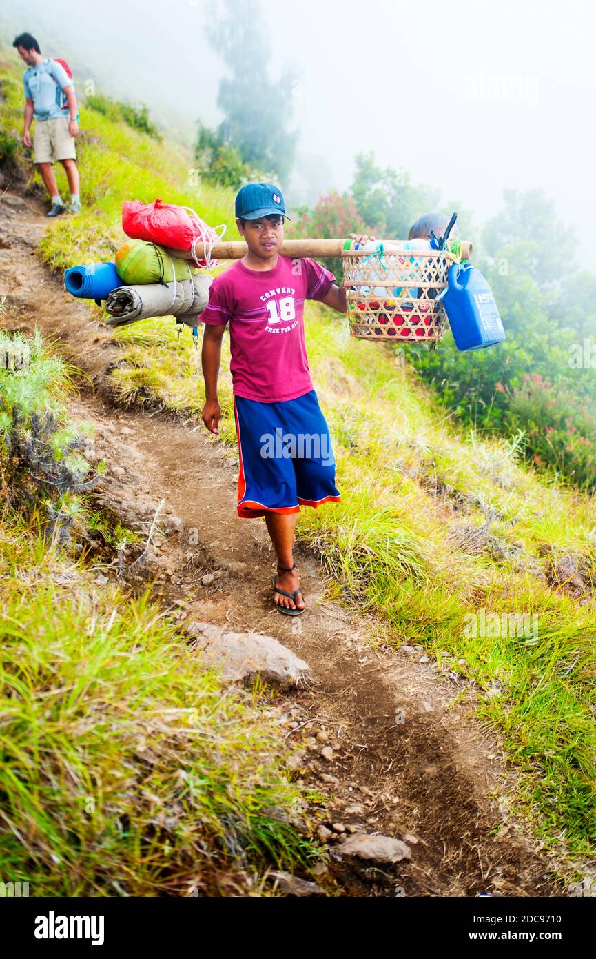Jeune portier transportant de la nourriture et du matériel de camping sur le Trek jusqu'au mont Rinjani, Lombok, Indonésie, Asie Banque D'Images