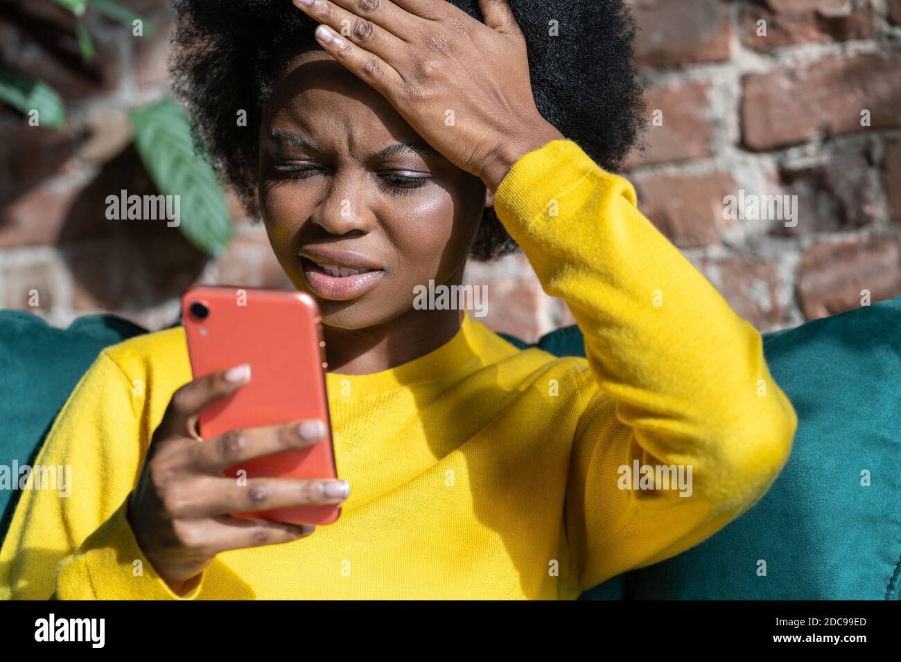 Confuse Afro-américaine femme millénaire faisant le geste de facepalm, touchant la tête avec la paume, regardant l'écran de téléphone mobile, a envoyé un courriel à la mauvaise adresse Banque D'Images
