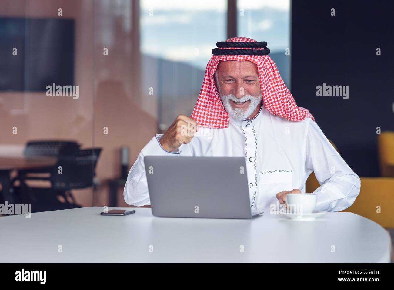 Homme d'affaires arabe célébrant la victoire au bureau avec un ordinateur portable. Banque D'Images