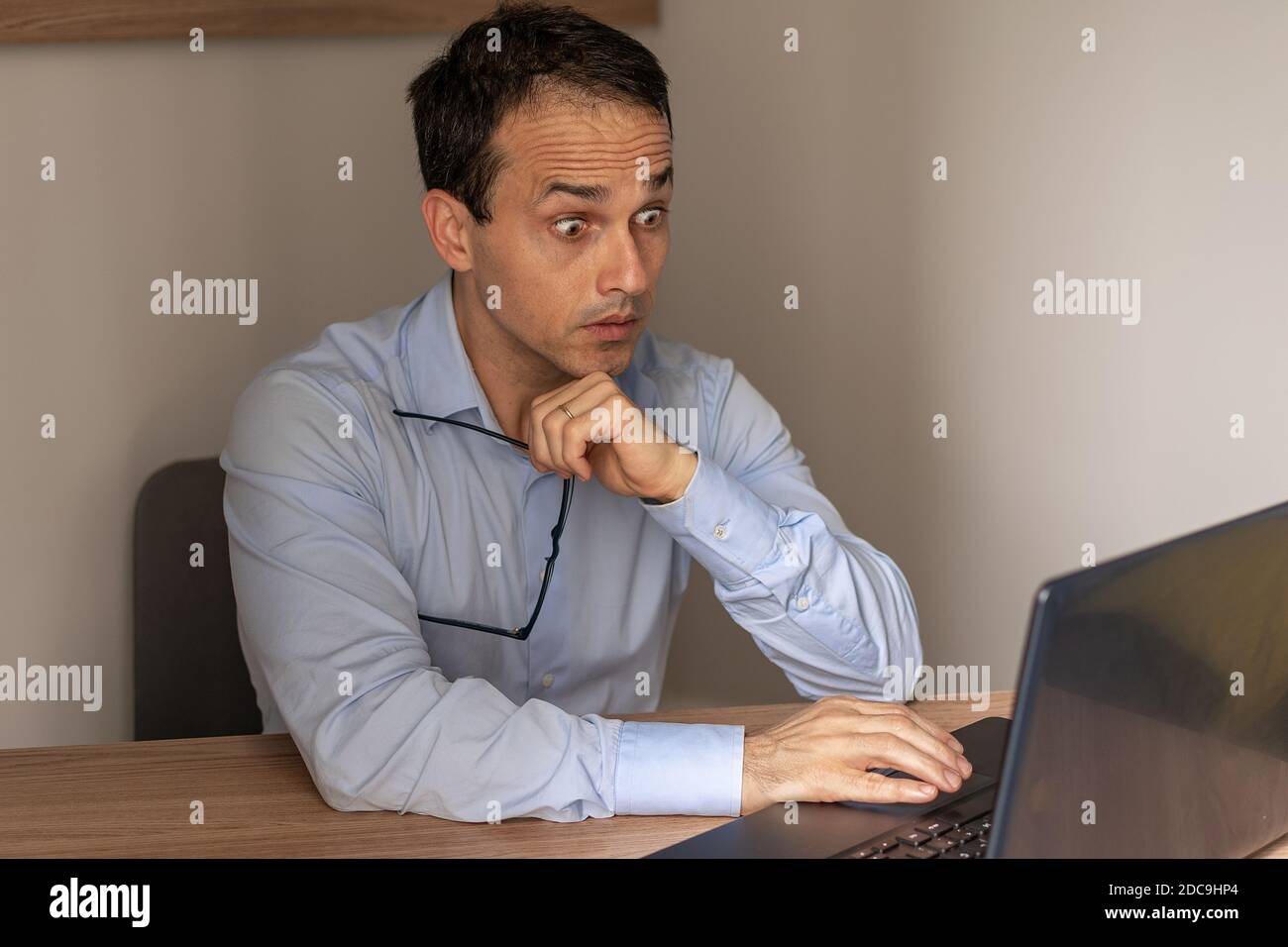 Homme mûr aux yeux renflés regardant son ordinateur portable. Banque D'Images