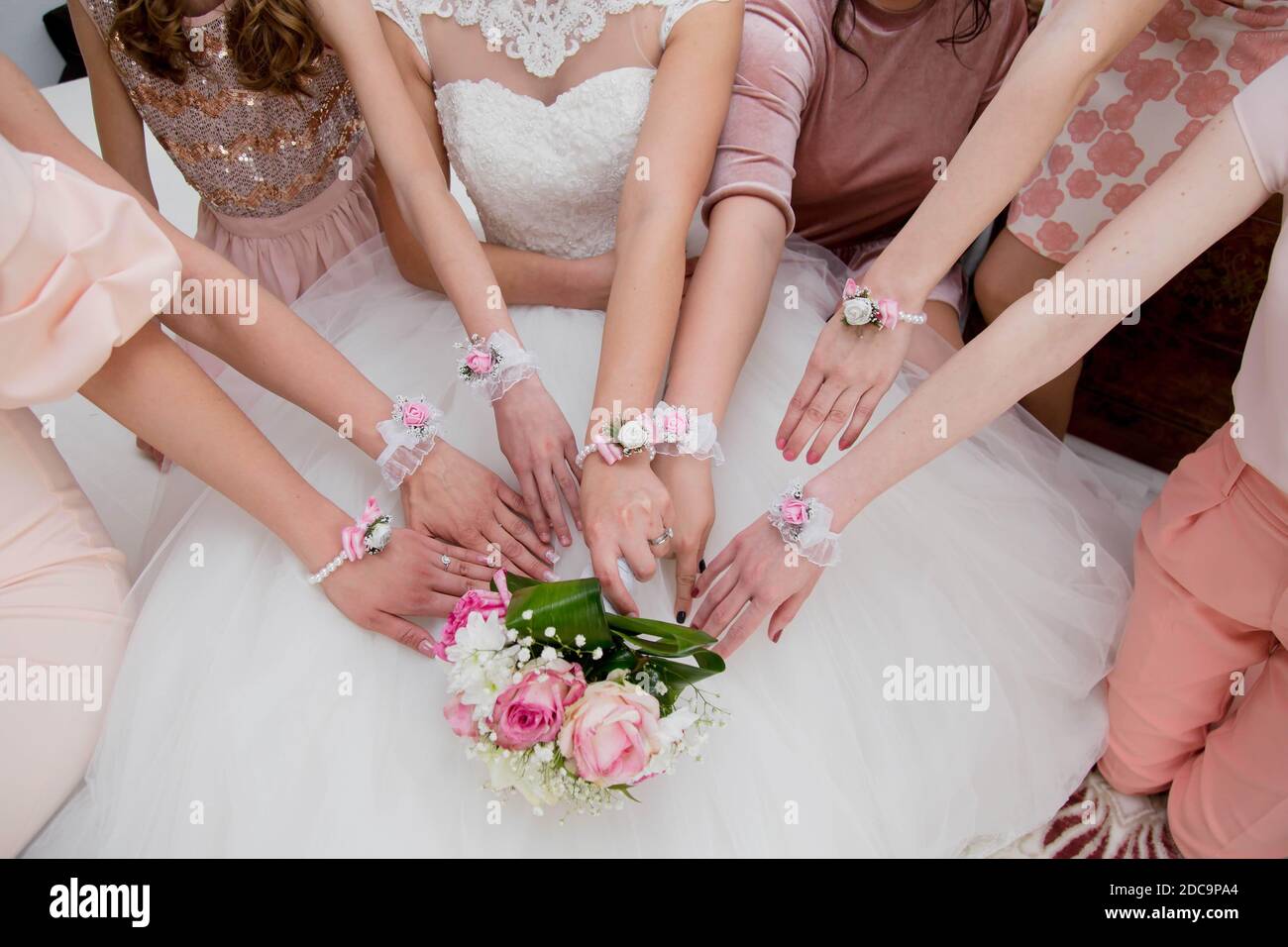 Une vue de dessus des mains de la mariée et des demoiselles d'honneur avec bracelets de couleur Banque D'Images