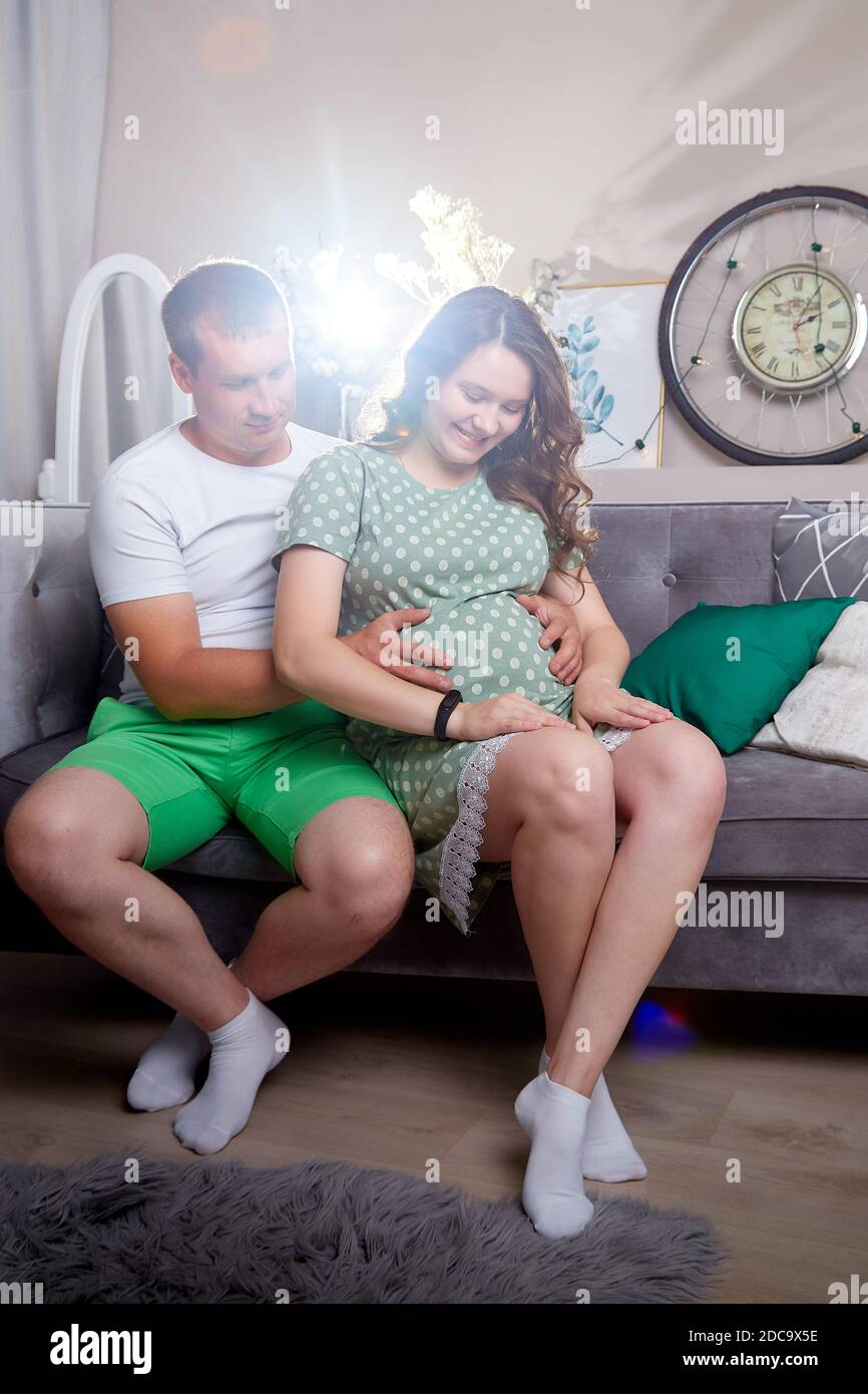 Couple mignon comprenant une femme enceinte et un homme attentionné dans le salon ensemble. Belle enceinte future mère et père à la maison Banque D'Images