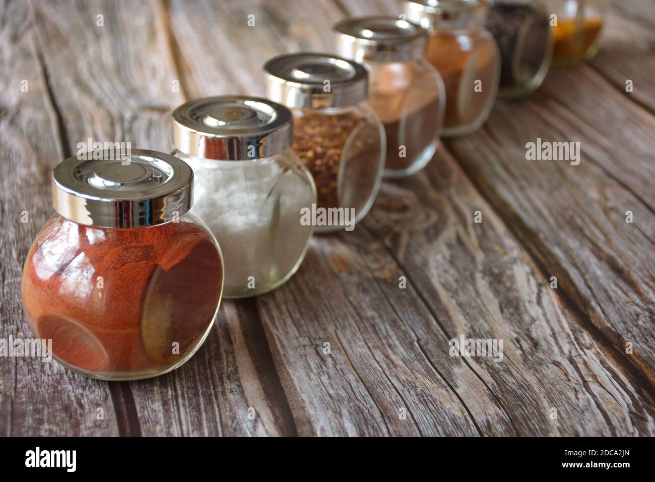 Diverses herbes et épices colorées dans un récipient en verre sur bois arrière-plan Banque D'Images