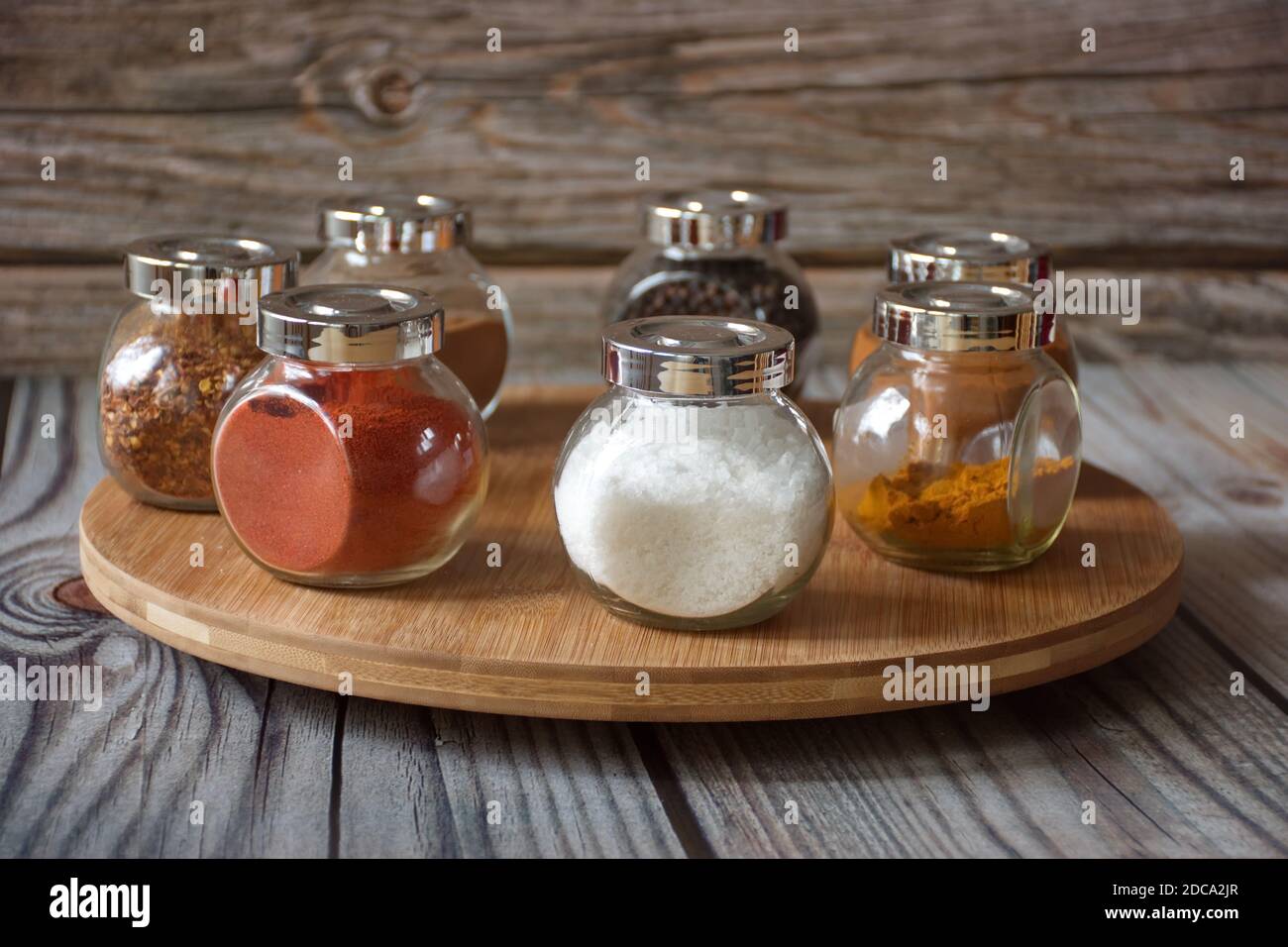 Diverses herbes et épices colorées dans un récipient en verre sur bois arrière-plan Banque D'Images