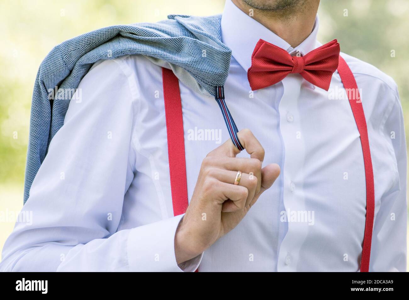 Le marié dans une chemise blanche avec un noeud rouge cravate et bretelles  pour tenir une veste Photo Stock - Alamy