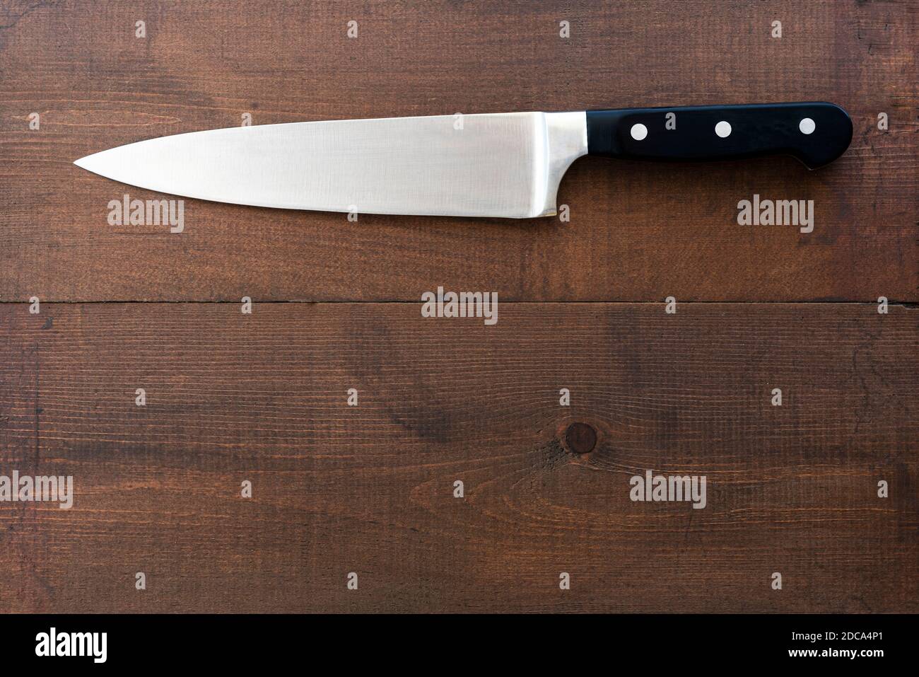 Grand couteau à découper en acier inoxydable, sur une ancienne table de travail en bois. Banque D'Images