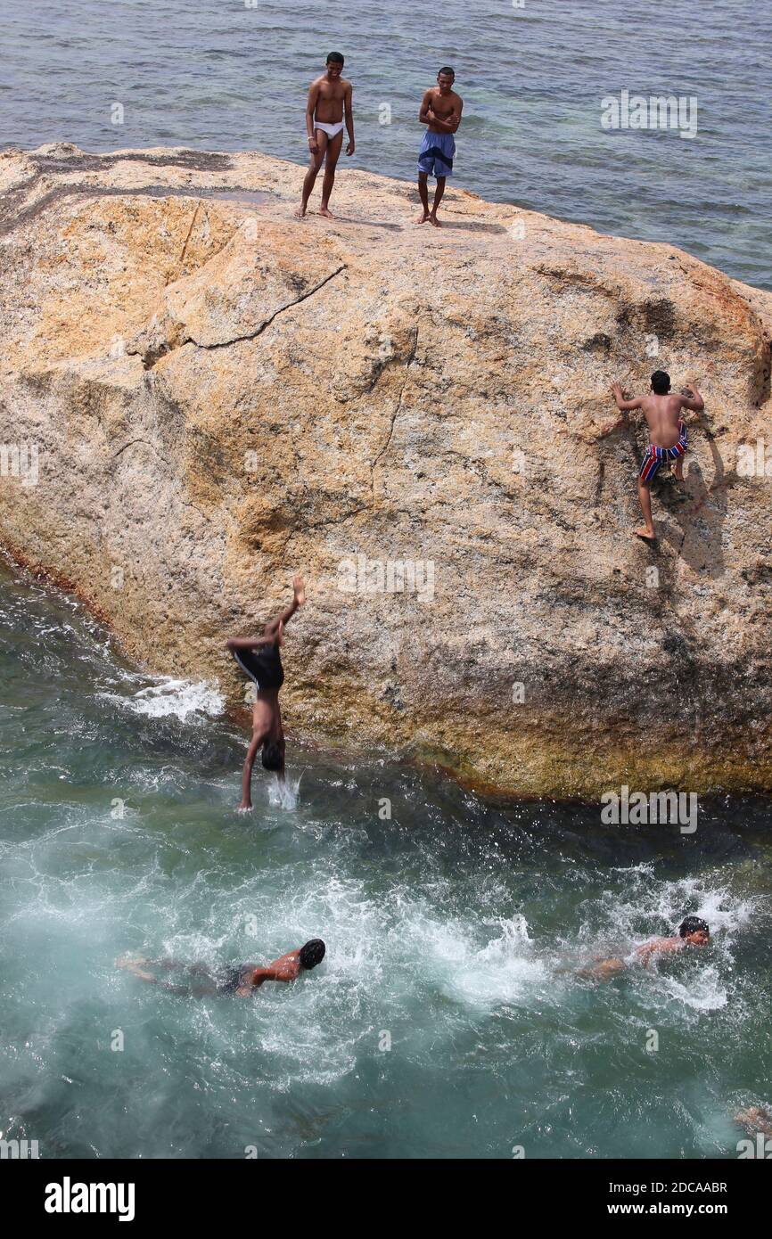 Jeunes hommes et garçons qui sautent dans la mer depuis UN rocher au large de la côte de Galle, Sri Lanka Banque D'Images