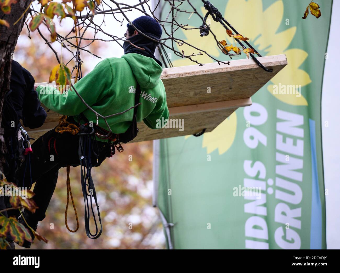 Wiesbaden, Allemagne. 20 novembre 2020. Un activiste flotte devant le drapeau de Bündnis90/Die Grünen. Des militants de Robin Wood, organisme de protection de l'environnement et de la nature, ont occupé deux arbres devant le siège du parti des Verts de Hesse dans la capitale de l'État. L'organisation proteste contre les clearings dans le cadre de l'expansion de l'A49 et veut rappeler aux Verts de Hesse leur responsabilité politique. Credit: Andreas Arnold/dpa/Alay Live News Banque D'Images