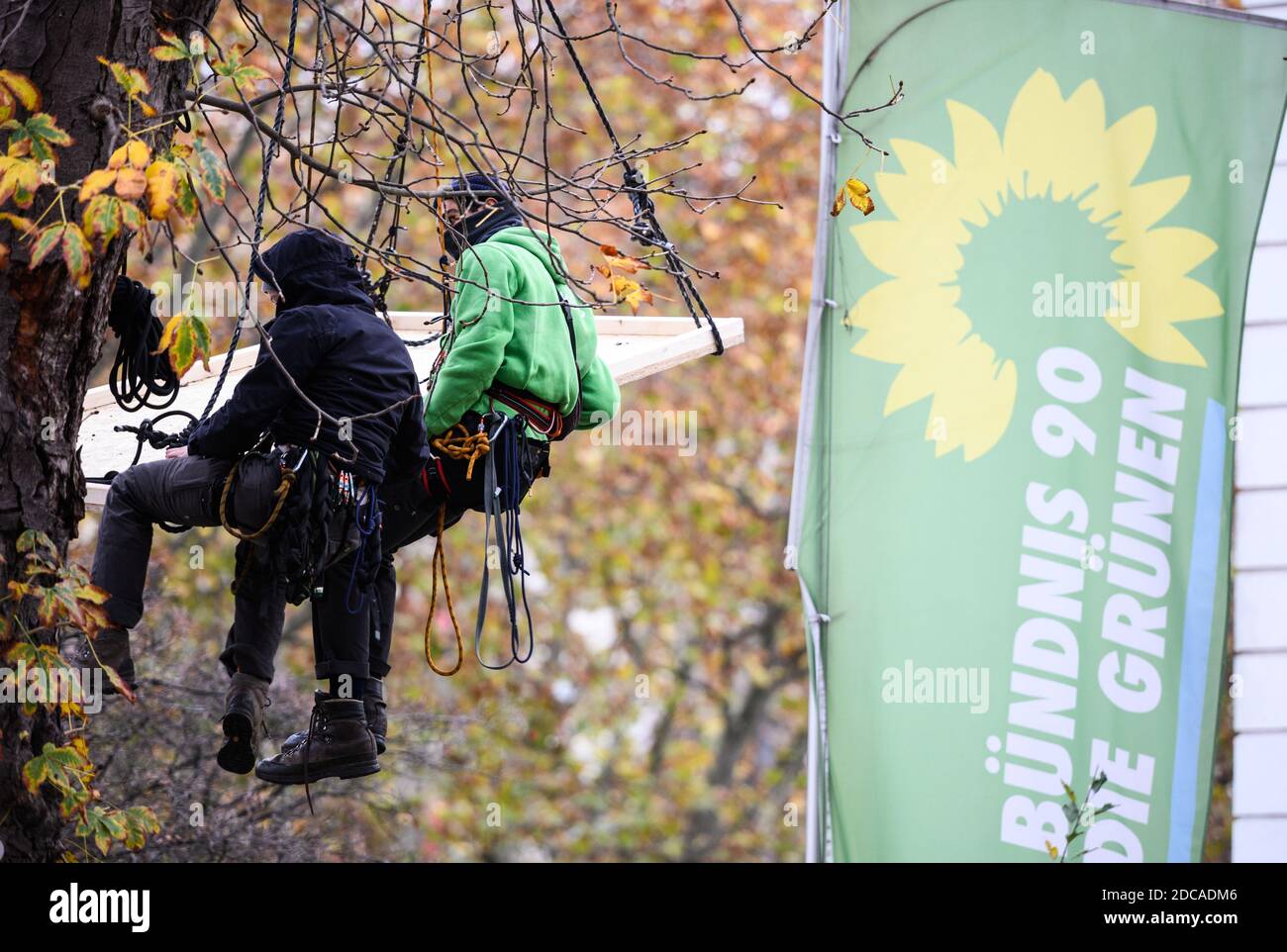 Wiesbaden, Allemagne. 20 novembre 2020. Deux activistes volent devant le drapeau de Bündnis90/Die Grünen. Des militants de Robin Wood, organisme de protection de l'environnement et de la nature, ont occupé deux arbres devant le siège du parti des Verts de Hesse dans la capitale de l'État. L'organisation proteste contre les clearings dans le cadre de l'expansion de l'A49 et veut rappeler aux Verts de Hesse leur responsabilité politique. Credit: Andreas Arnold/dpa/Alay Live News Banque D'Images