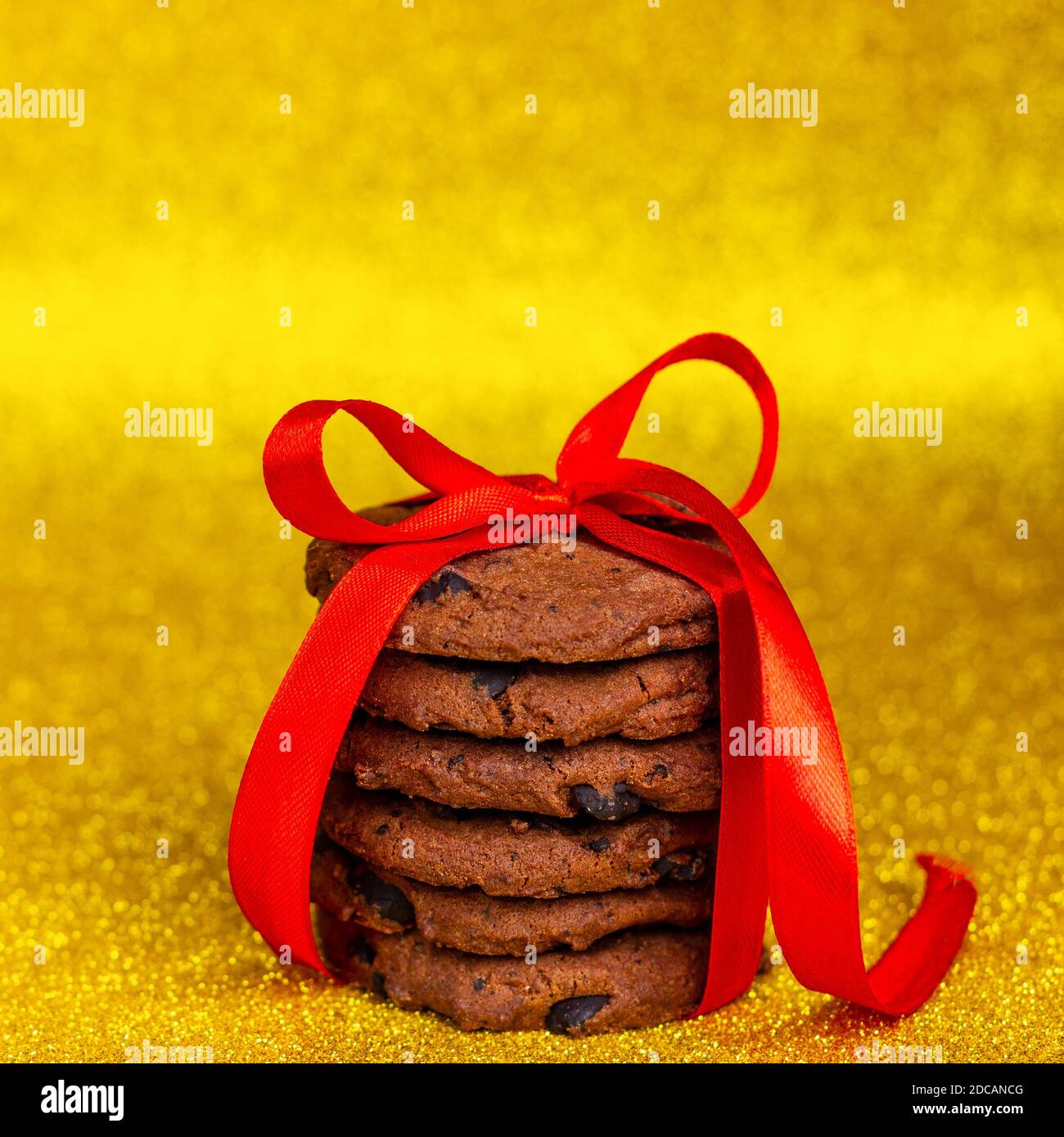 Biscuits aux pépites de chocolat faits maison avec un ruban rouge. Fond jaune brillant. Banque D'Images