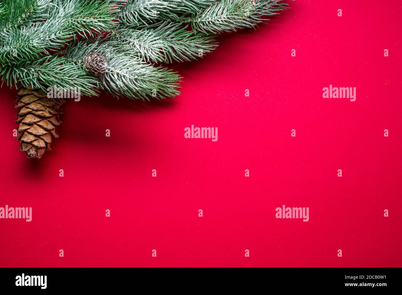 Fond rouge nouvel an ou Noël avec branche de sapin couverte de neige et décor de Noël. Vue de dessus. Banque D'Images