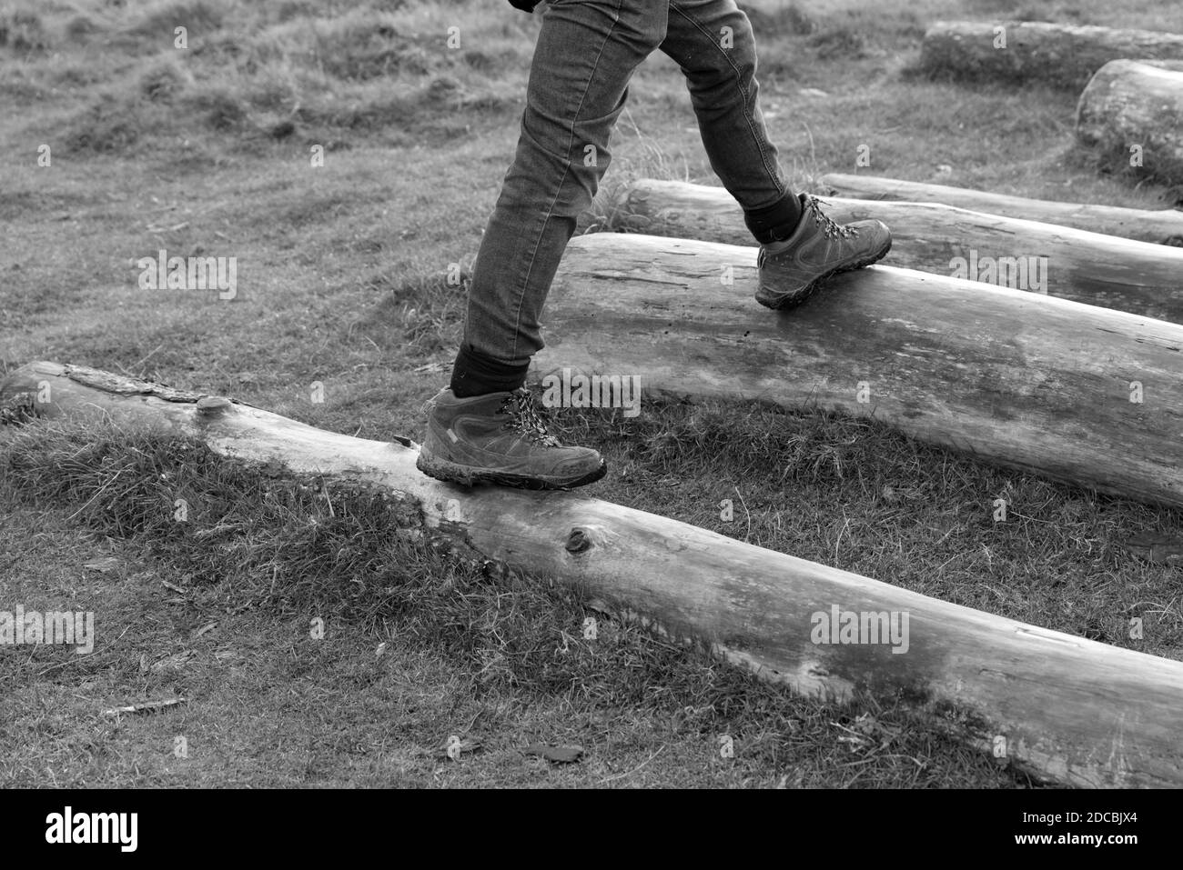 image en noir et blanc des jambes et des pieds qui s'y sont mis Tronc d'arbre de bois à l'extérieur portant des bottes de randonnée.Homme marchant à l'extérieur faire de l'exercice en hiver Banque D'Images