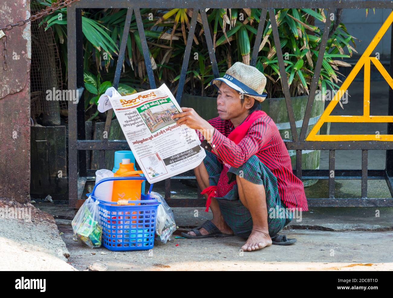 La vie quotidienne au Myanmar - un jeune homme lisant des journaux à Yangon, Myanmar (Birmanie), en Asie, en février Banque D'Images