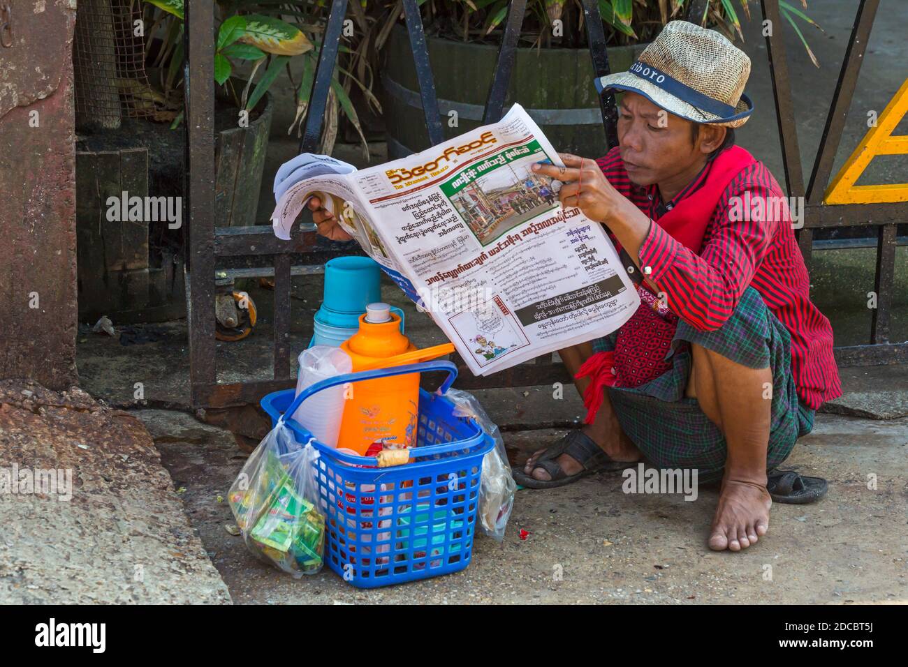 La vie quotidienne au Myanmar - un jeune homme lisant des journaux à Yangon, Myanmar (Birmanie), en Asie, en février Banque D'Images