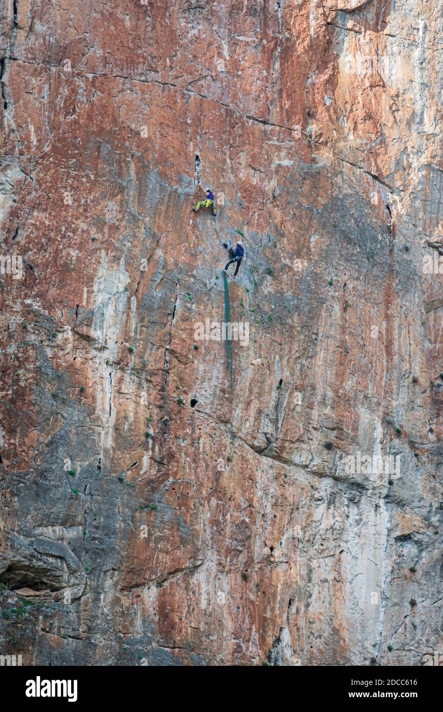 Deux athlètes pratiquant l'escalade sur un mur vertical et haut au-dessus du sol. Banque D'Images