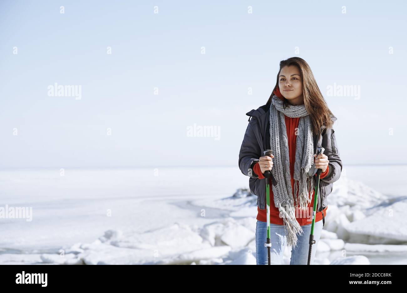 Jeune femme adulte à l'extérieur voyageant dans un paysage glacé avec sac à dos et bâtons de marche Banque D'Images