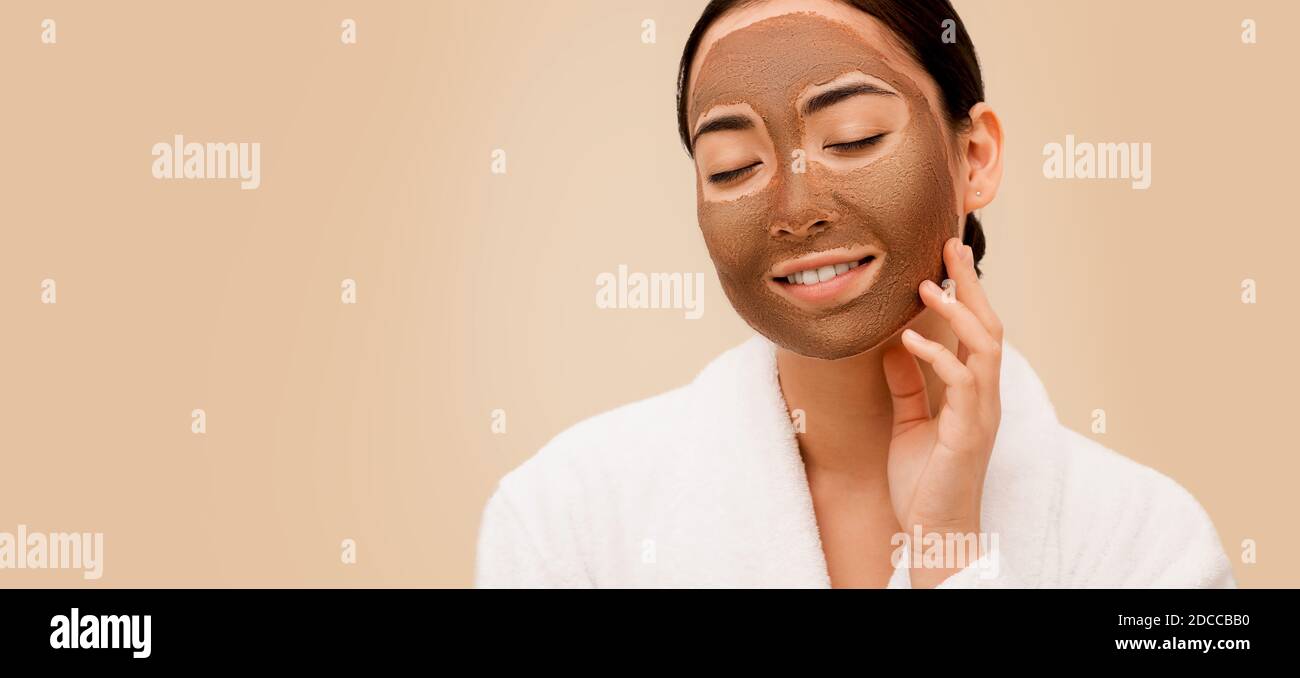Femme asiatique avec un masque de boue sur son visage. Traitement, nettoyage et ramollissement de la peau féminine Banque D'Images