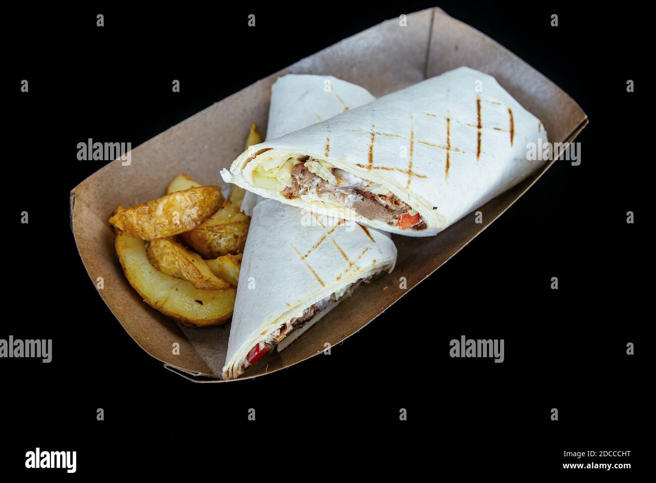 Le pita shawarma est rempli de légumes à base de viande, de assaisonnements et de sauce. Avec des frites. Dans une assiette en papier. Banque D'Images