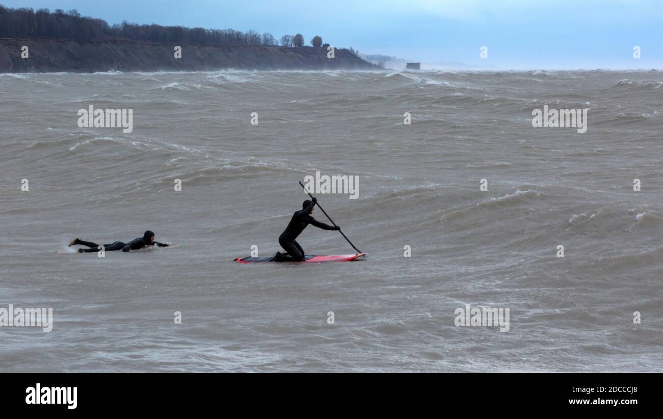 Paddle surf dans des conditions de tempête extrême avec des vagues élevées, Port Stanley Ontario Canada sur la rive nord du lac Érié. Banque D'Images