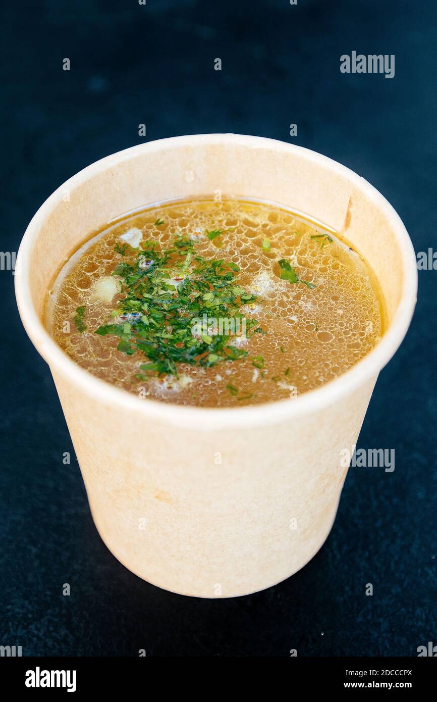 Bouillon de poulet dans une tasse de papier sur fond sombre Banque D'Images