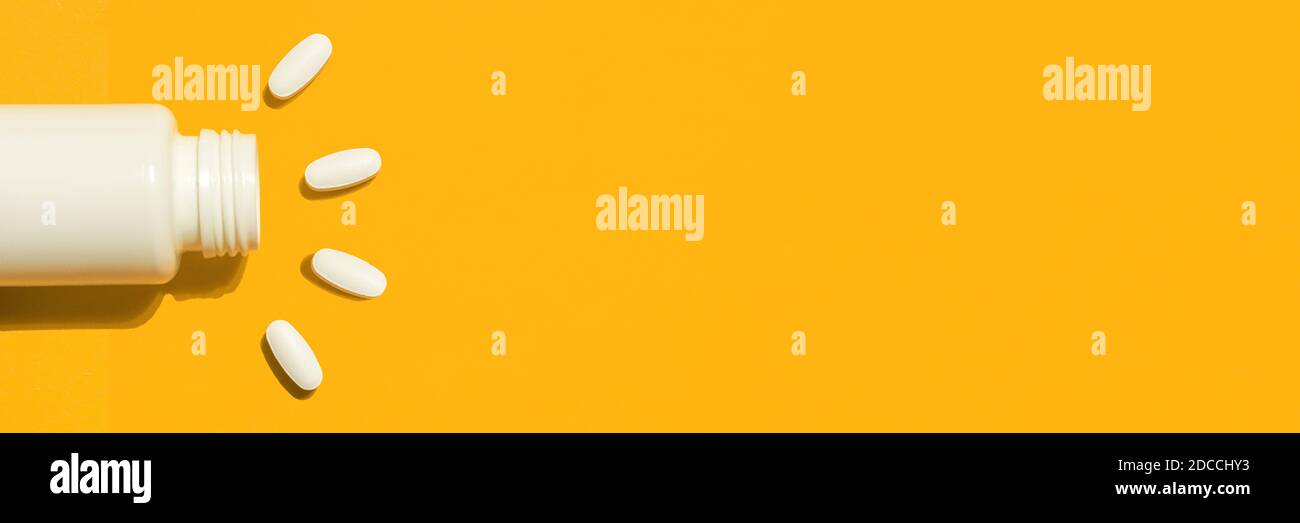 Bannière avec des pilules médicales blanches et des comprimés qui se répandent hors d'une bouteille en plastique. Médecine concepts créatifs. Arrière-plan orange. Flat lay, espace de copie Banque D'Images