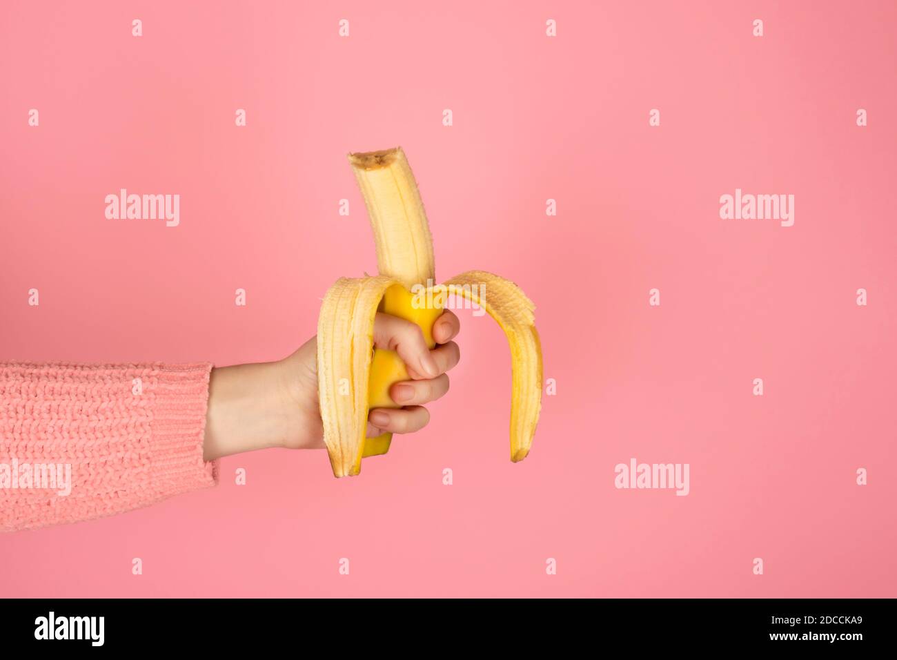 La main femelle contient une banane bitten jaune vif. Bannière monochrome tendance avec espace de copie Banque D'Images