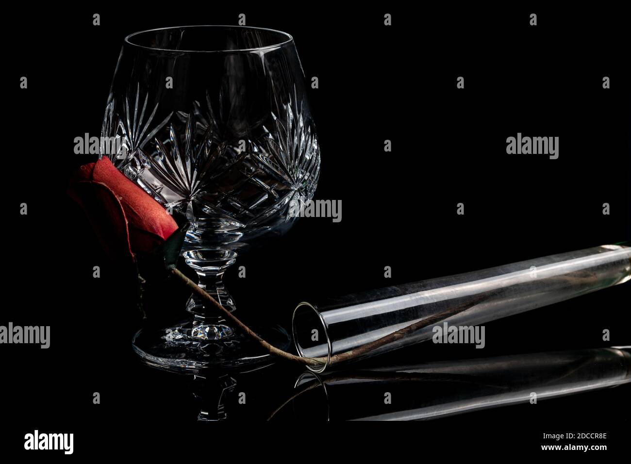 Vase et verre de brandy en cristal vide avec une rose sur un fond noir foncé et un éclairage spectaculaire. Verre à boire isolé et raffiné Banque D'Images